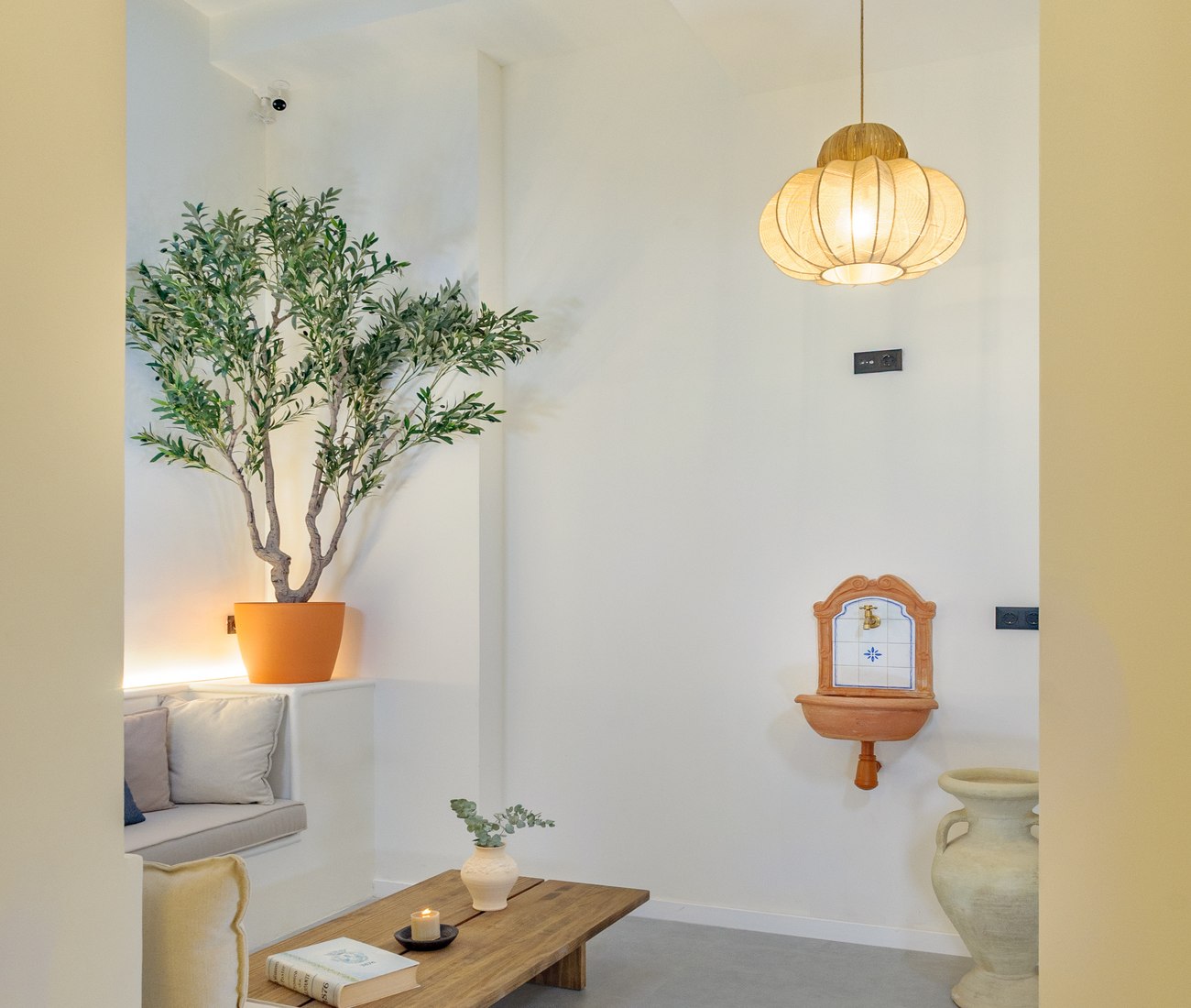 Alma House entrance hall with olive tree, wooden bench and terracotta fountain