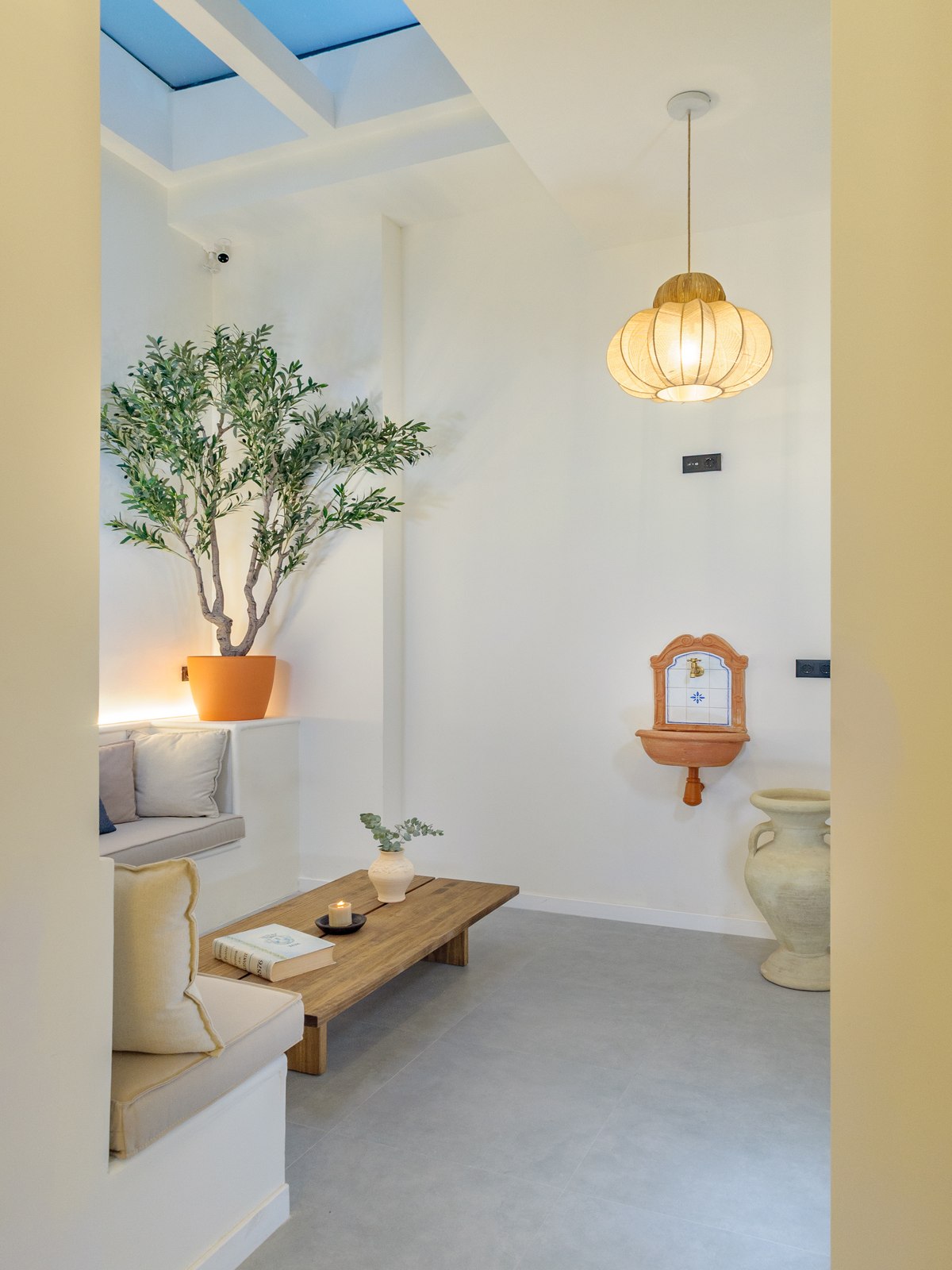 Alma House entrance hall with olive tree, wooden bench and terracotta fountain