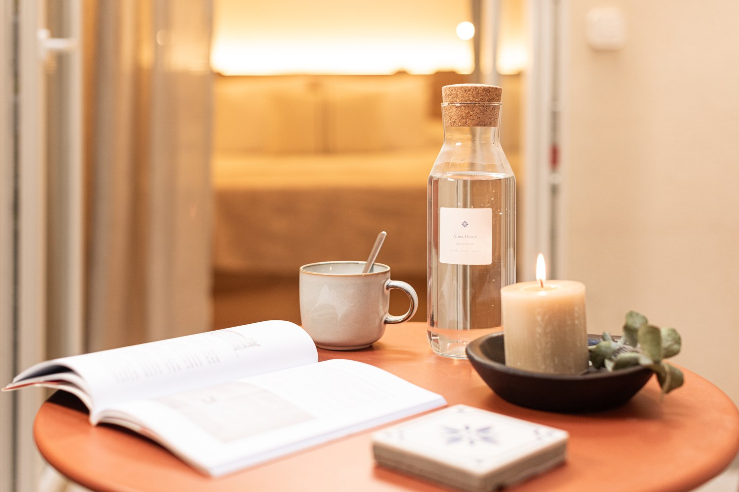 Side table with book, reusable bottle and candle in an Alma House suite