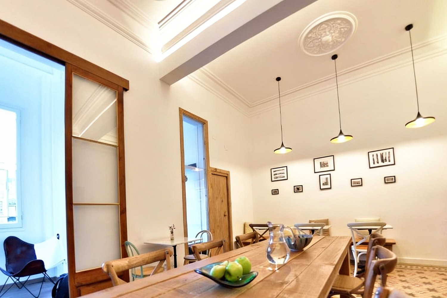 Comedor con mesa de madera, lámparas y rosetón, Hostal Girona