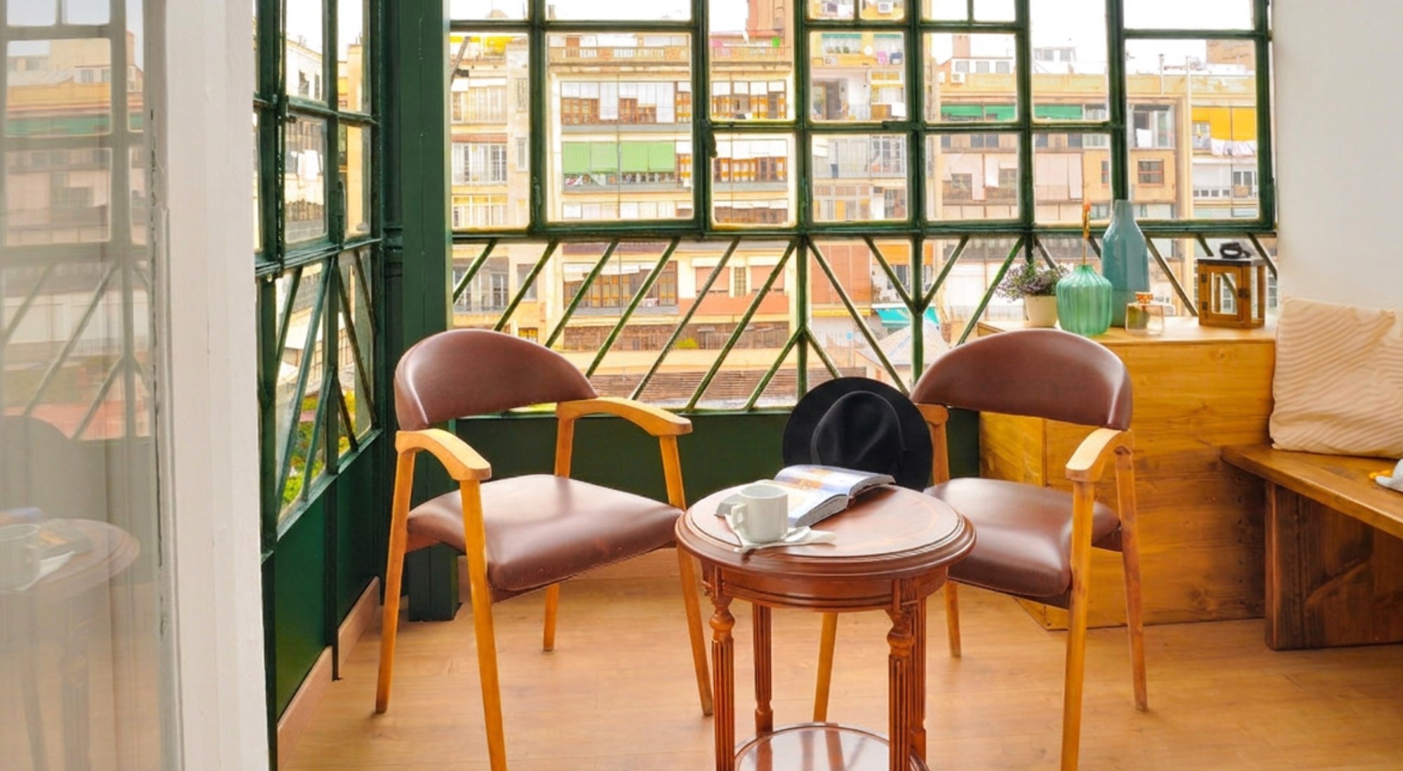 Galería de Hostal Girona con sillas de cuero y cristalera verde